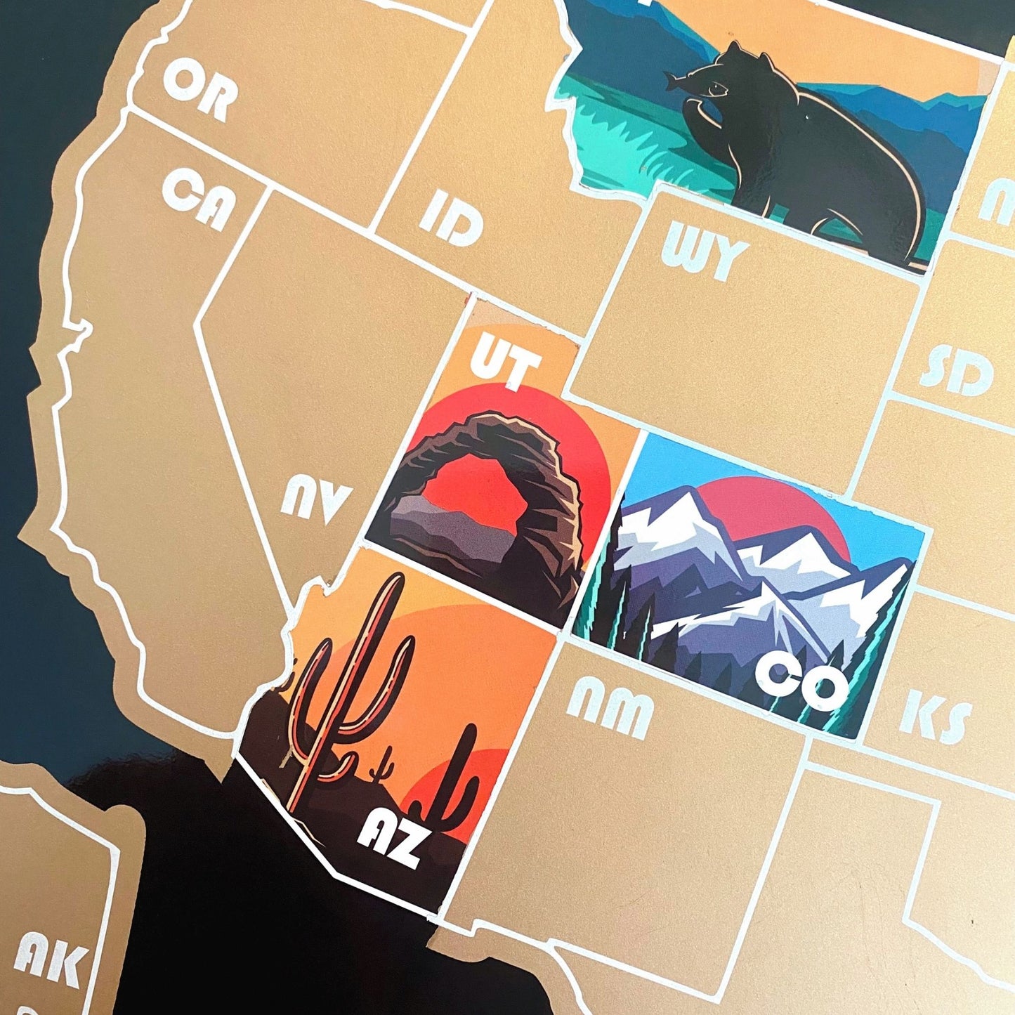 Close up of USA Map with Black background. Each state has a icon representing the state. Gold Overlay scratches off to reveal artwork underneath.