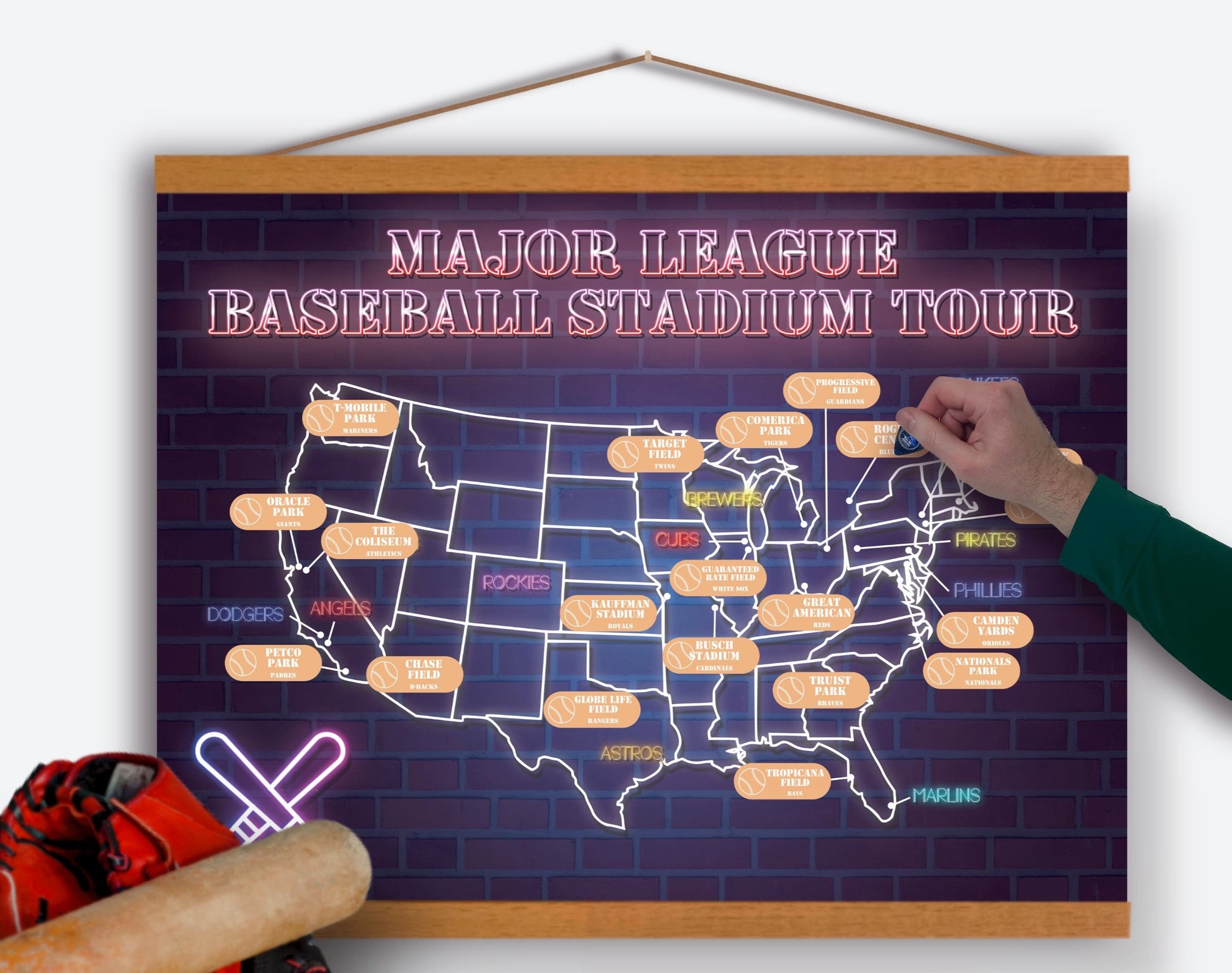 USA Baseball Stadium Scratch off Poster. Has a purple brick background with a USA map.  Each stadium is listed with a gold layer to scratch off once you have visited. Hanging on a 20in wooden frame.