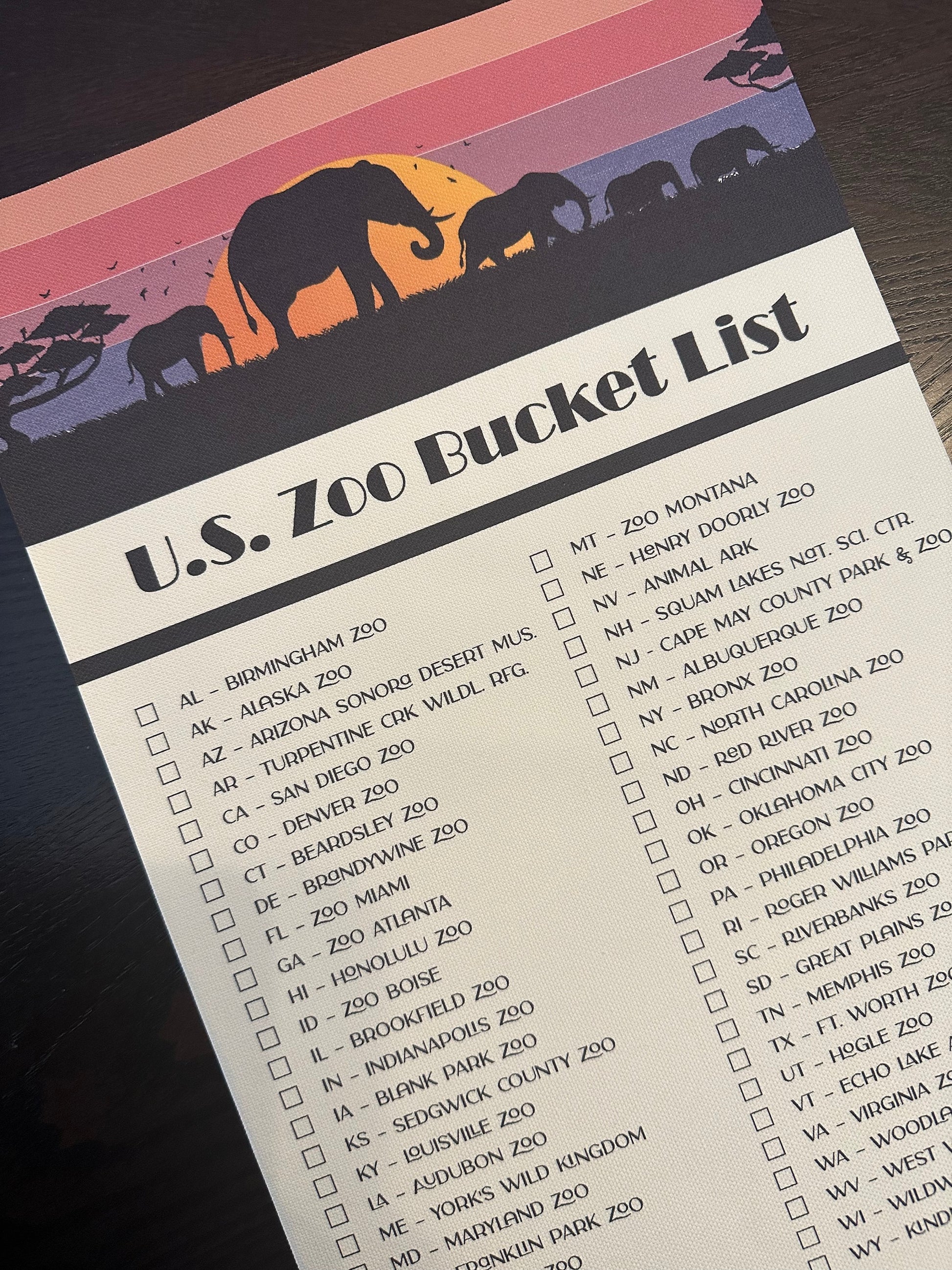 U.S. Zoo Bucket List Checklist Tracker with marker. Printed on canvas. Has a design on the top with a sunset and elephants.