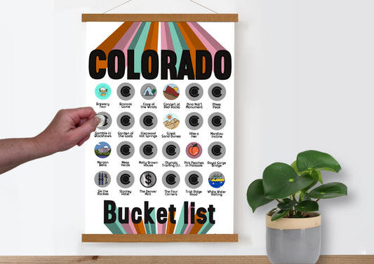 Colorado Bucket List scratch off poster.  Has icons for 30 iconic places in Colorado. Scratch off a silver layer to reveal artwork. Hanging on a wooden frame.