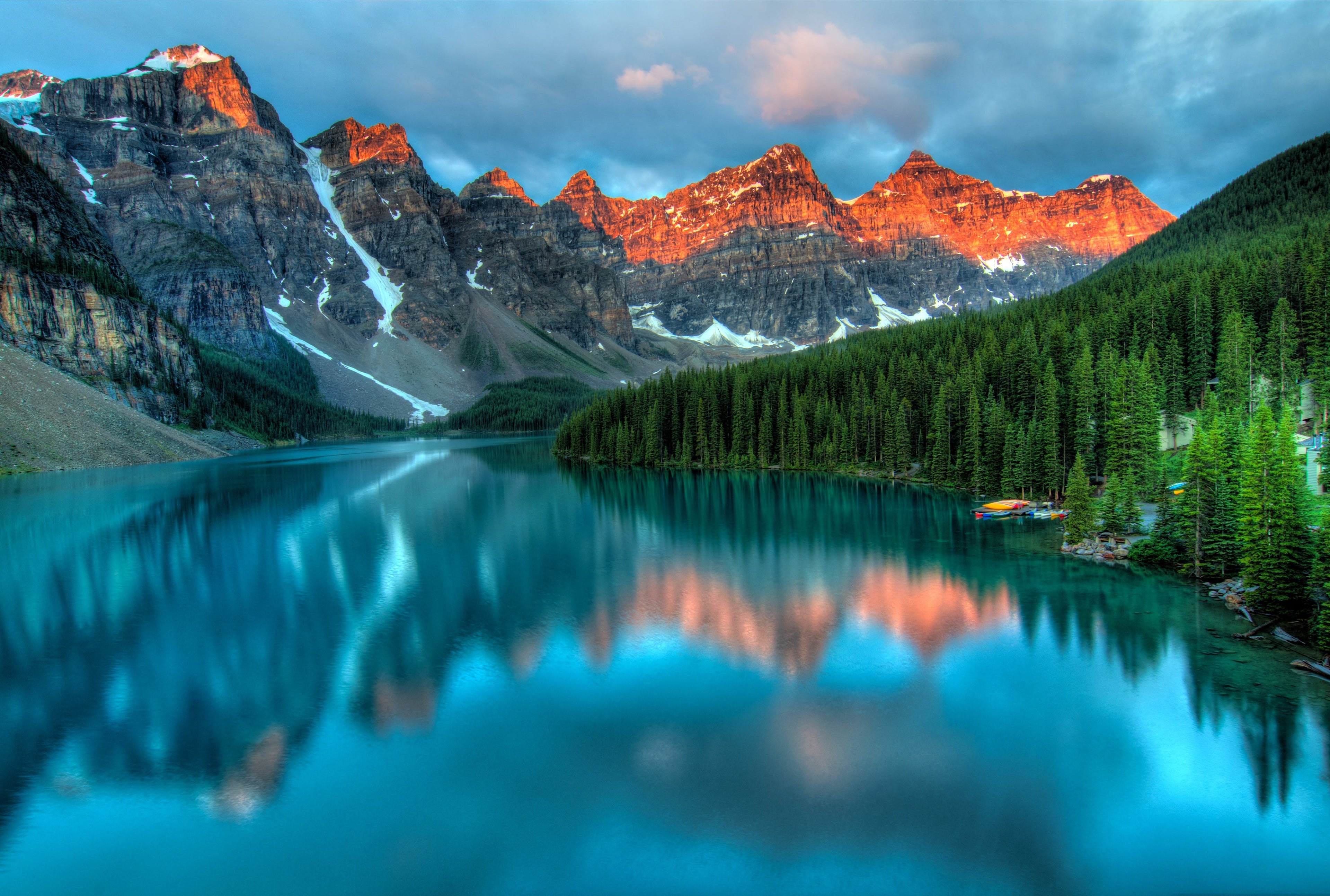 Mountains and lake, colors are blues, greens and rust.