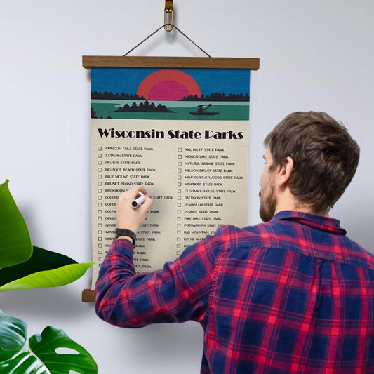 Wisconsin State Parks Checklist Tracker. Printed on canvas. Has a design on the top with a sunset and canoe. Hanging on a wooden frame.